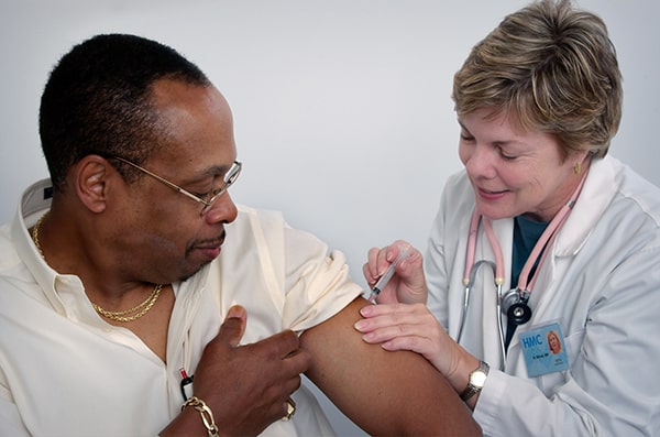 Homem sendo vacinado por uma enfermeira