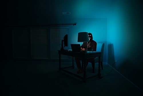 Hacker trabalhando em uma mesa com luminária de luz azul