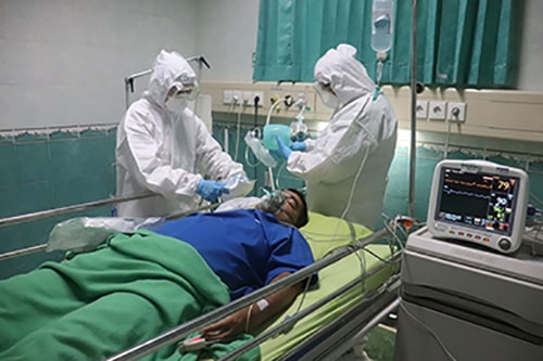 Dois médicos utilizando equipamento de proteção tratando paciente