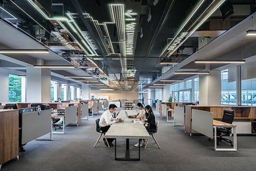 Três funcionários trabalhando em um escritório enorme e vazio