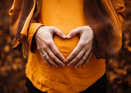 Mulher grávida faz símbolo decoração com as mãos