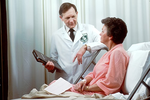 Paciente deitada na maca conversa com seu médico