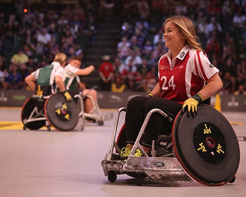 mulher feliz de cadeira de rodas jogando basquete adaptado