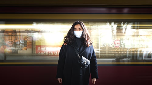 Mulher usando máscara em frente ao vagão do metrô